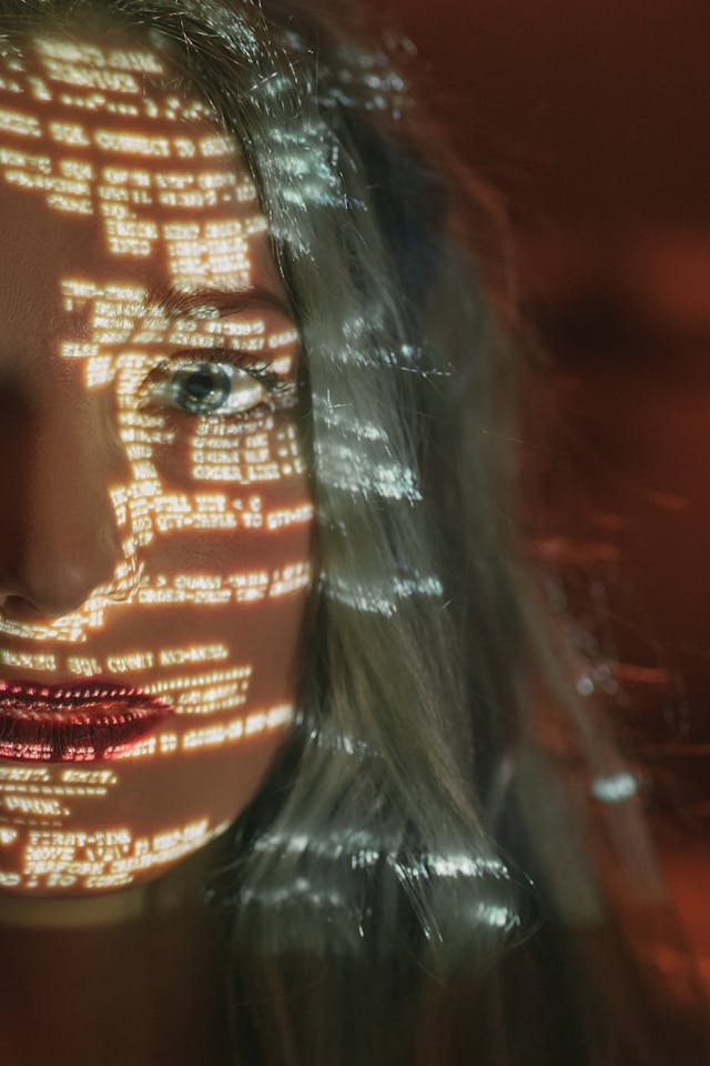 Girl with light beam of code on her face.